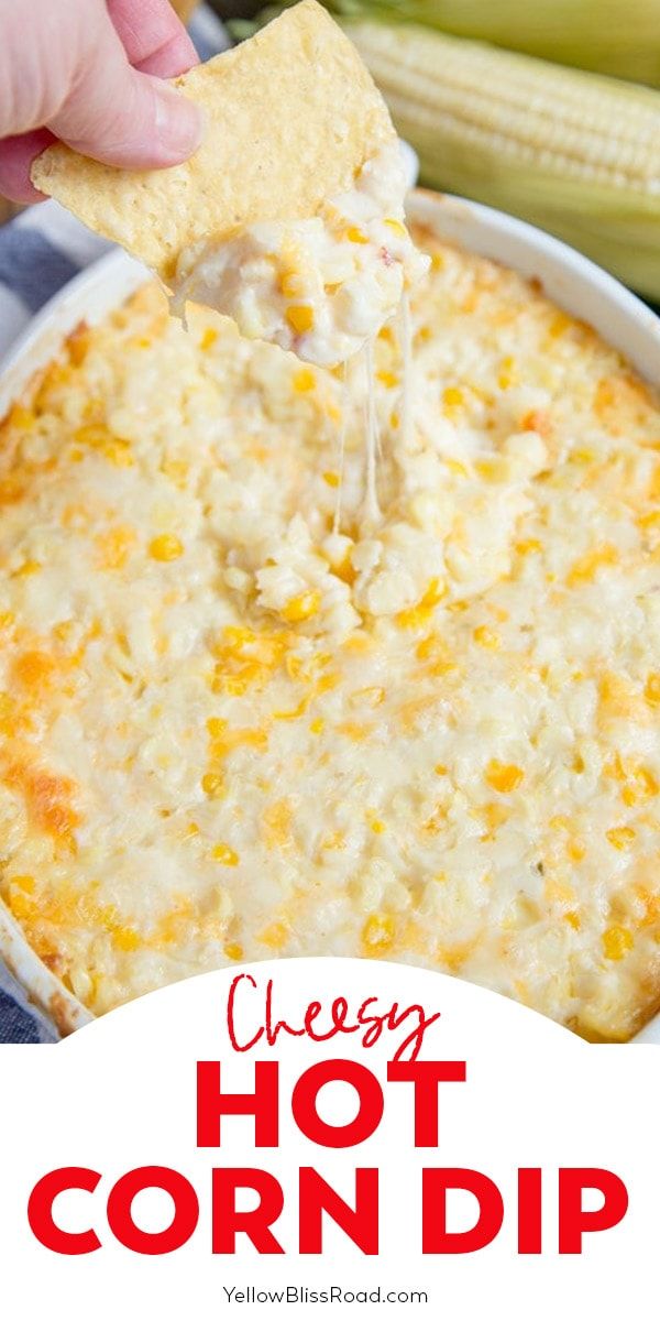 cheesy hot corn dip in a white bowl with a hand holding a tortilla chip