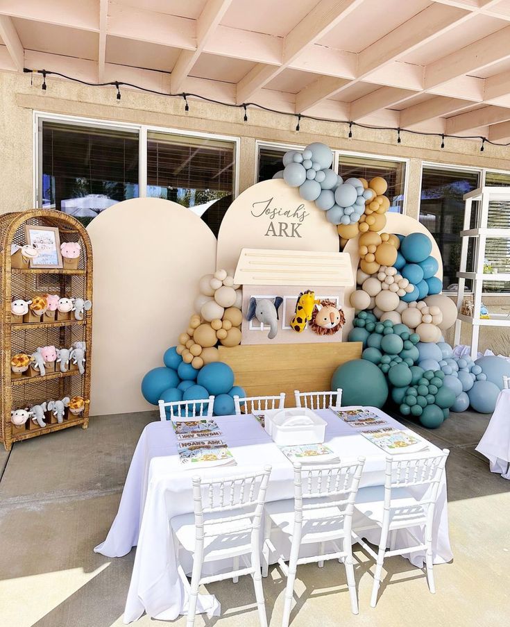 a table set up for an event with balloons and decorations on the wall behind it