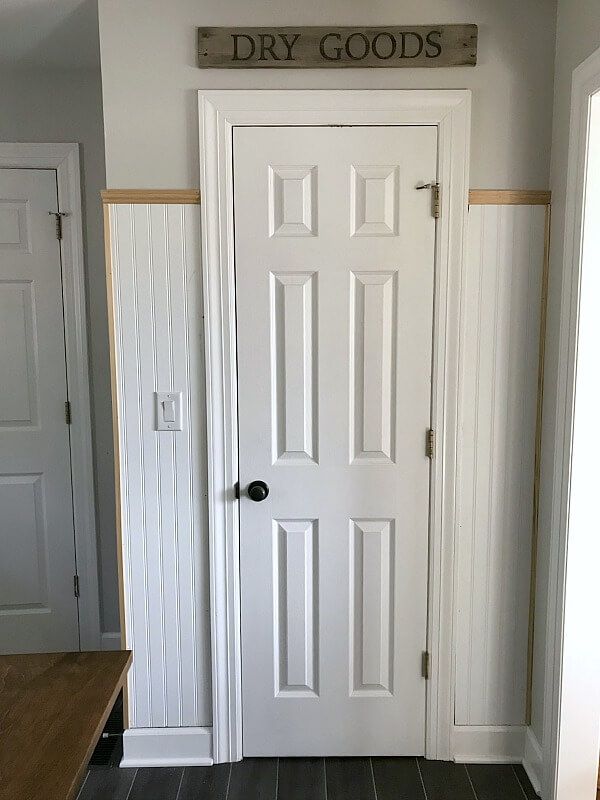 a white door with the words dry goods on it in front of a wooden bench