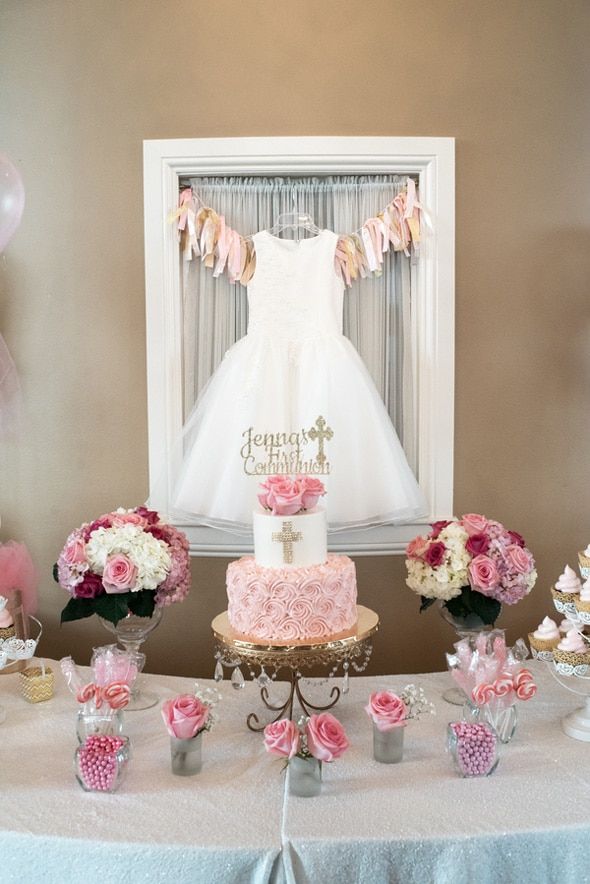 a table topped with a cake covered in pink and white flowers next to cupcakes