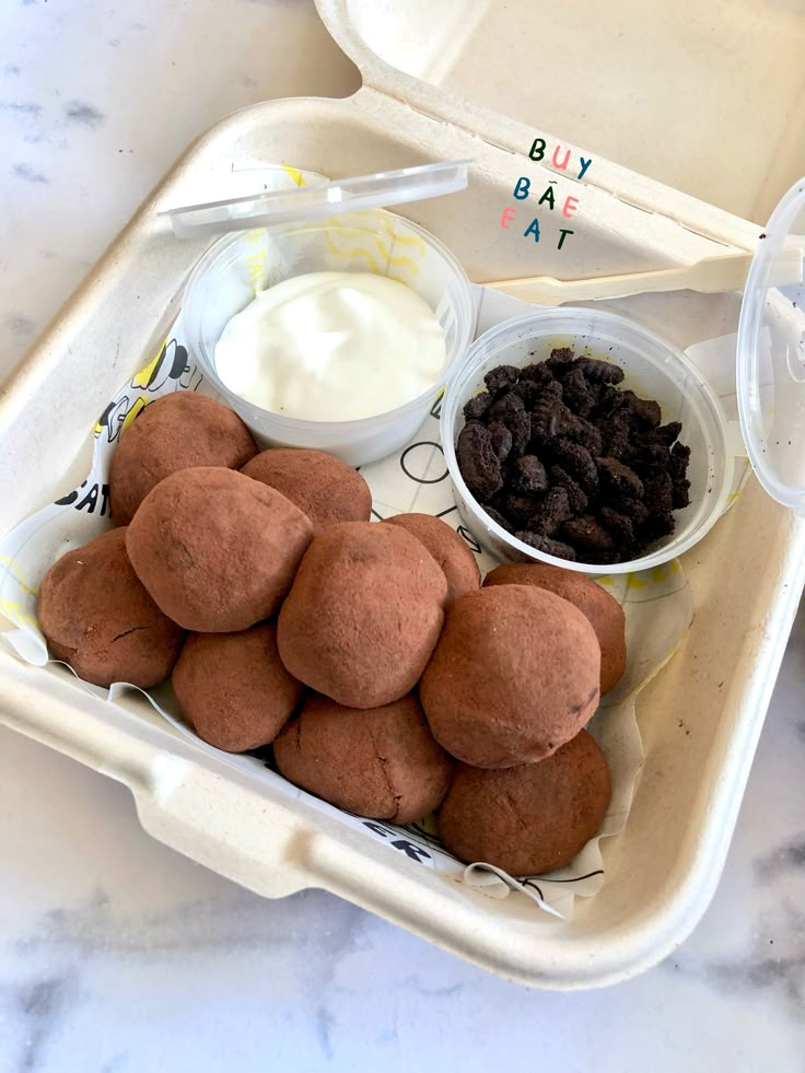 a tray filled with different types of food on top of a marble countertop next to a cup of yogurt and chocolate chips