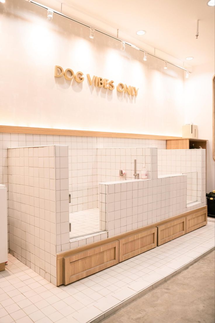 the inside of a dog washroom with white tile walls and wooden drawers on each side