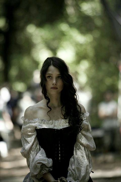 a woman in a dress is walking down the street with her hand on her hip