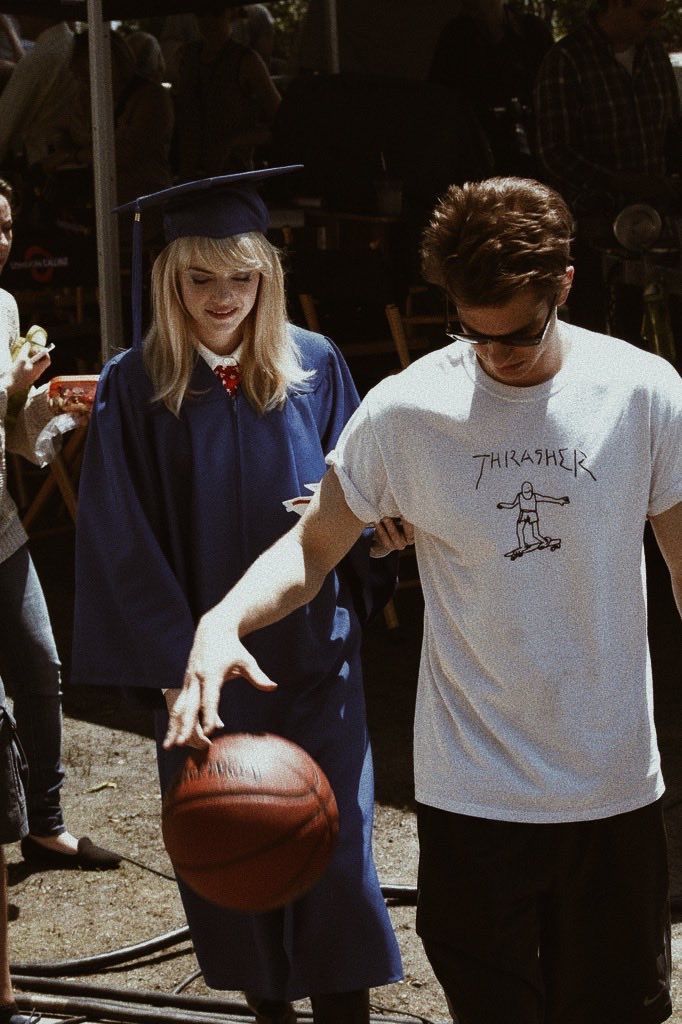 a young man holding a basketball while standing next to a woman in a graduation gown