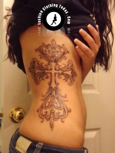 a woman with a cross tattoo on her lower back is standing in front of a door