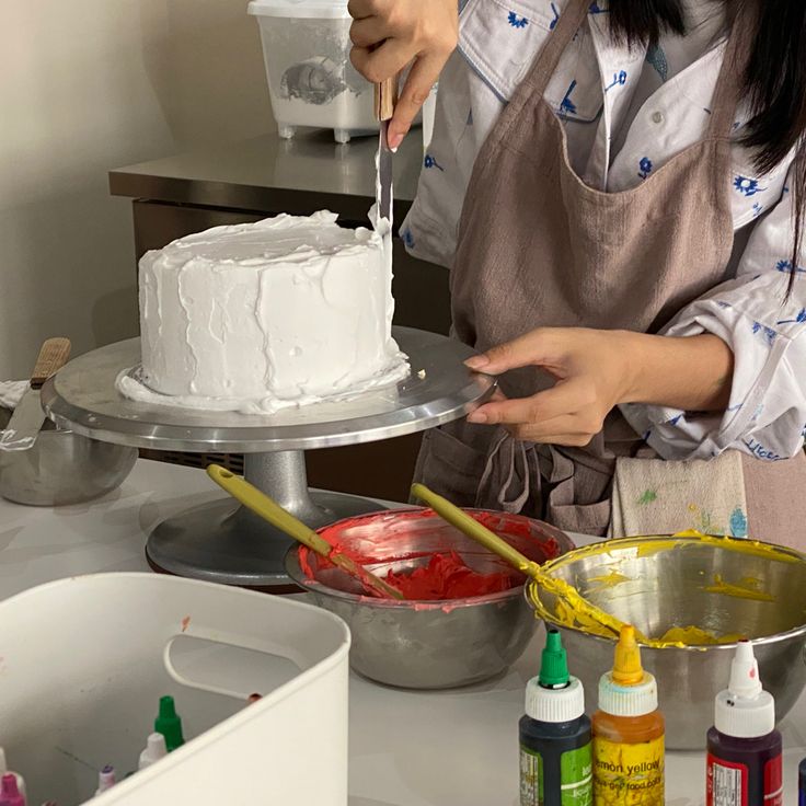 a woman in an apron decorating a cake