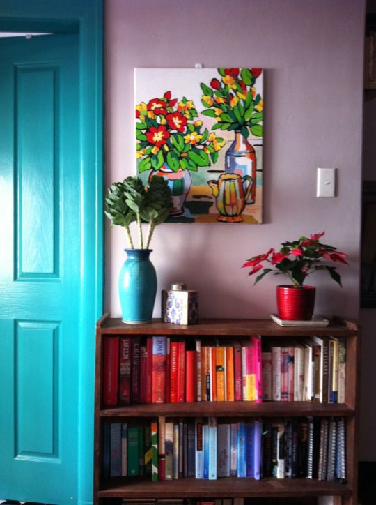 a bookshelf filled with lots of books next to a blue door and green doors