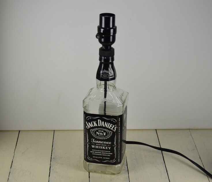 a bottle that is sitting on the floor next to a light bulb with a cord in it