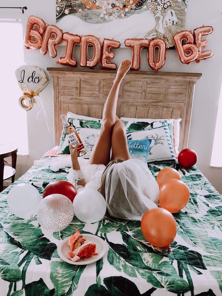 a woman laying on her bed with balloons and confetti in front of her