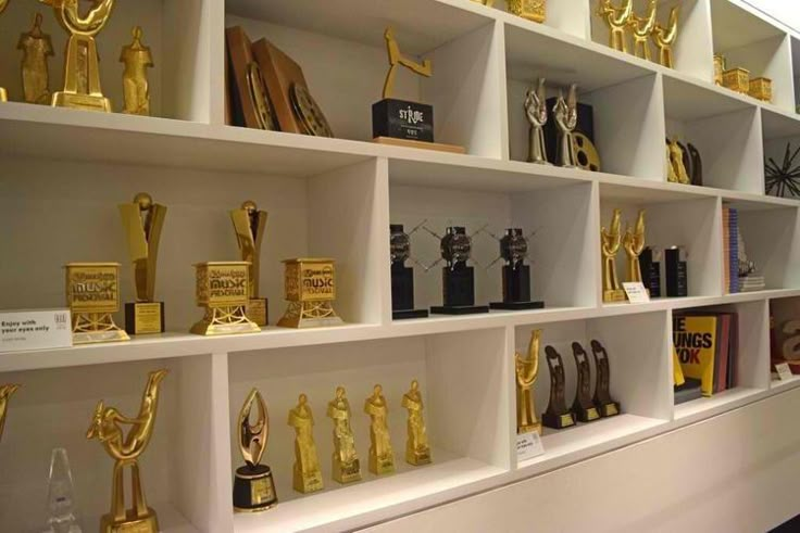 the shelves are filled with many different trophies and awards on display in front of each other