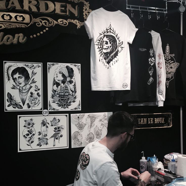 a man sitting at a table in front of some t - shirts and other items