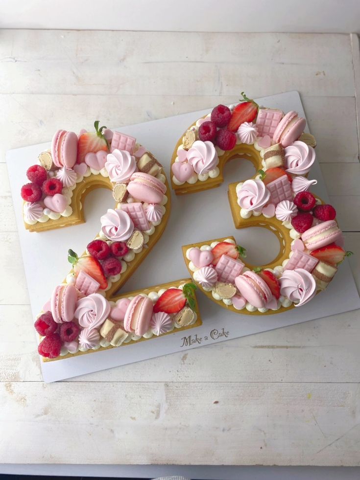 a cake shaped like the number twenty five with strawberries, raspberries and other toppings