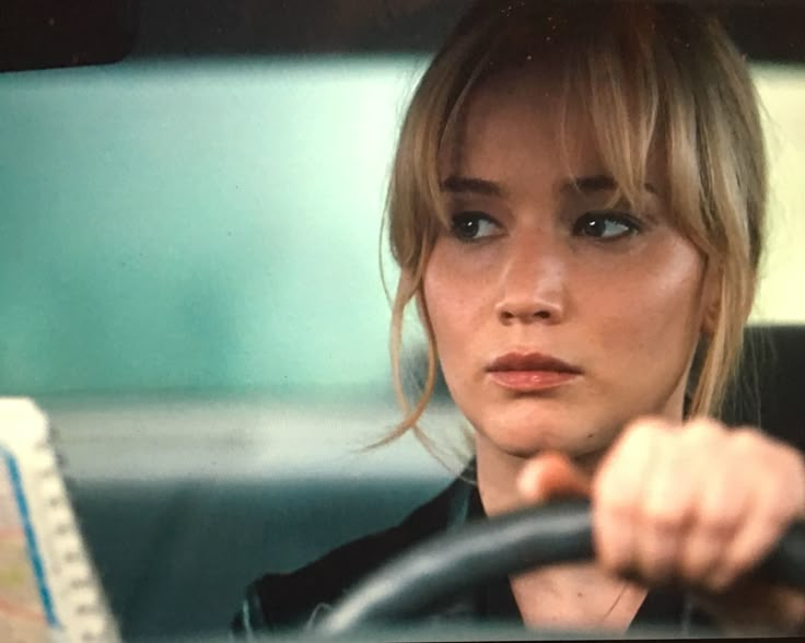 a woman driving a car with her hand on the steering wheel