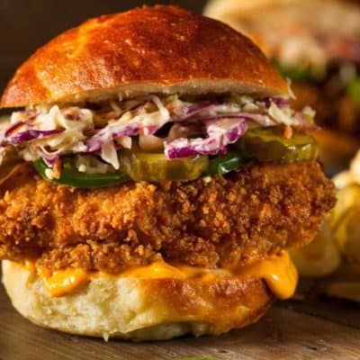 a fried chicken sandwich with coleslaw and pickles