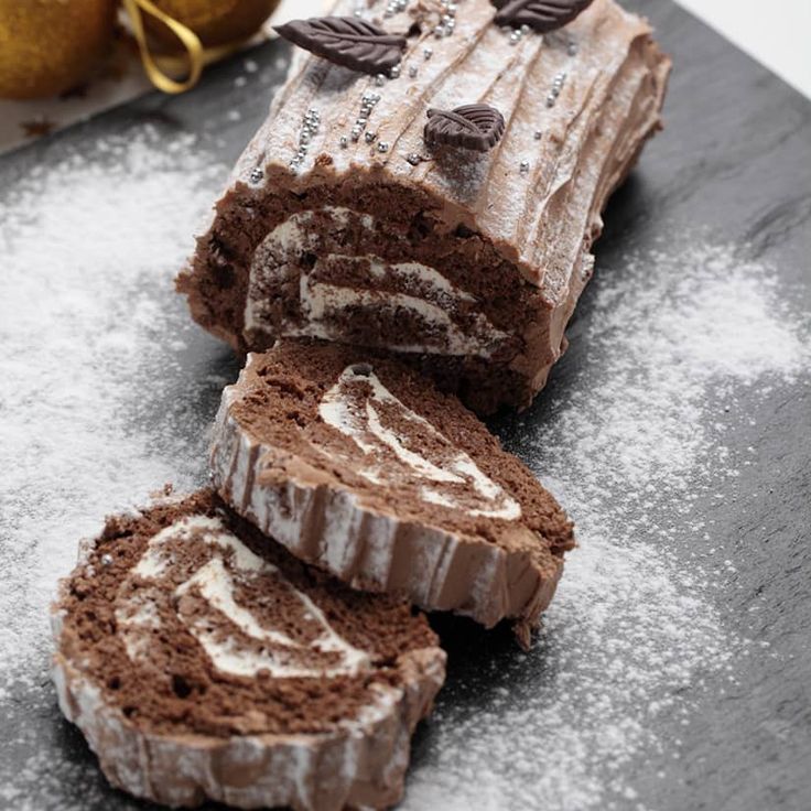 chocolate cake with white frosting and leaves cut in half on top of a table