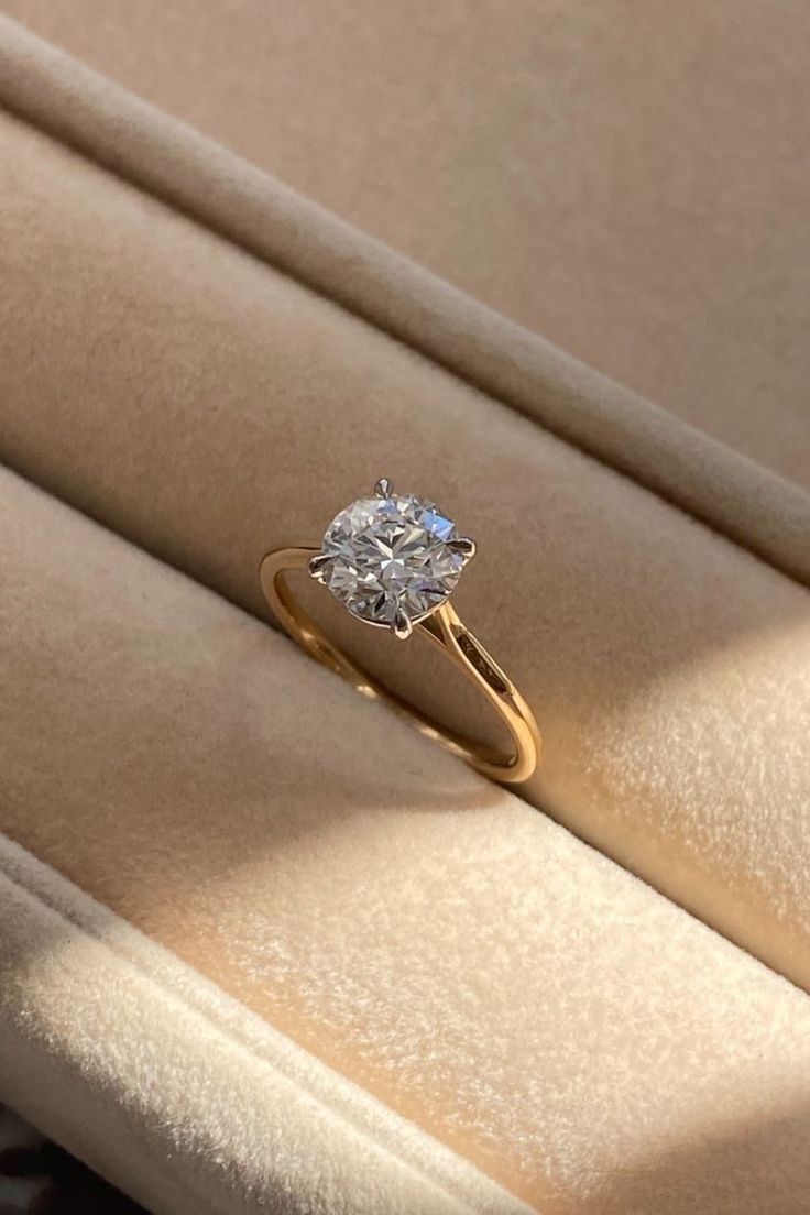 a diamond ring sitting on top of a beige velvet seat in a room with light coming through the window