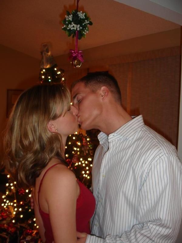 a man and woman kissing in front of a christmas tree