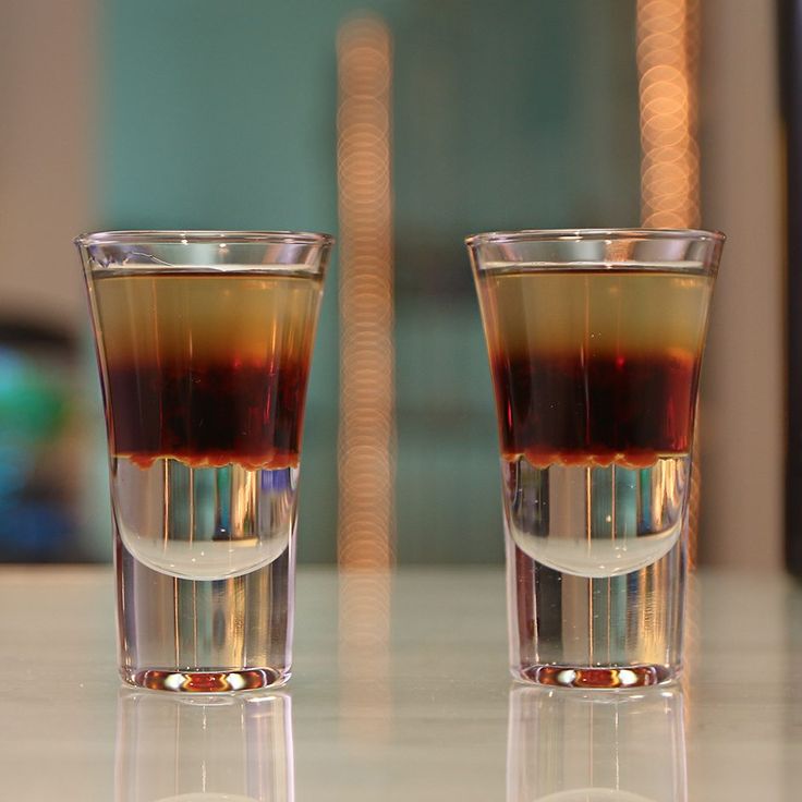 two shot glasses filled with liquid sitting on top of a white table next to each other