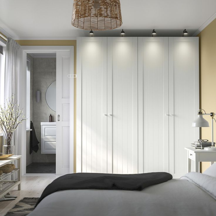 a bedroom with white closets and yellow accent walls, along with a black blanket on the bed