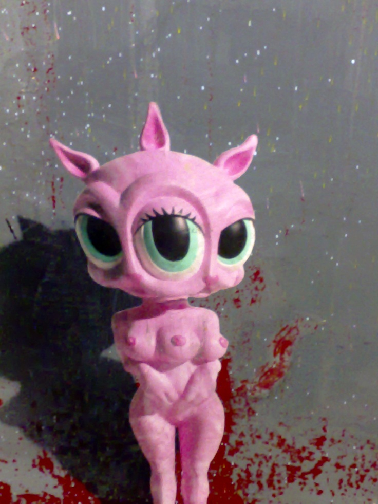 a pink doll with big eyes standing in front of a wall