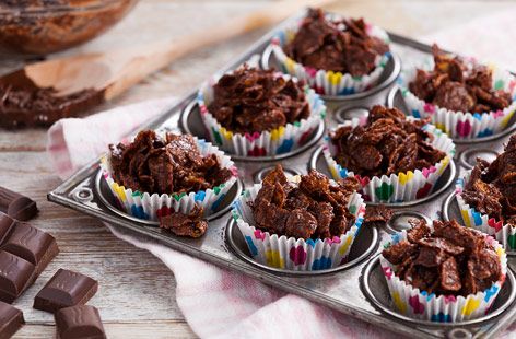 chocolate cupcakes are sitting on a baking tray next to some pieces of chocolate