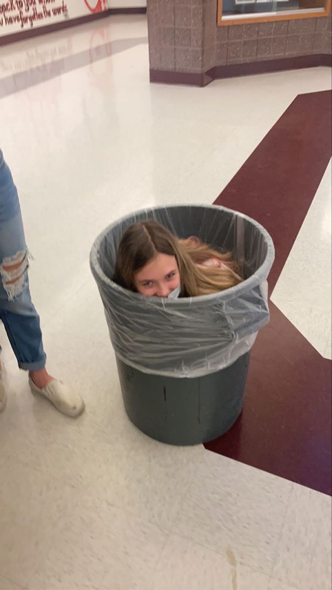 a girl in a trash can with her head inside