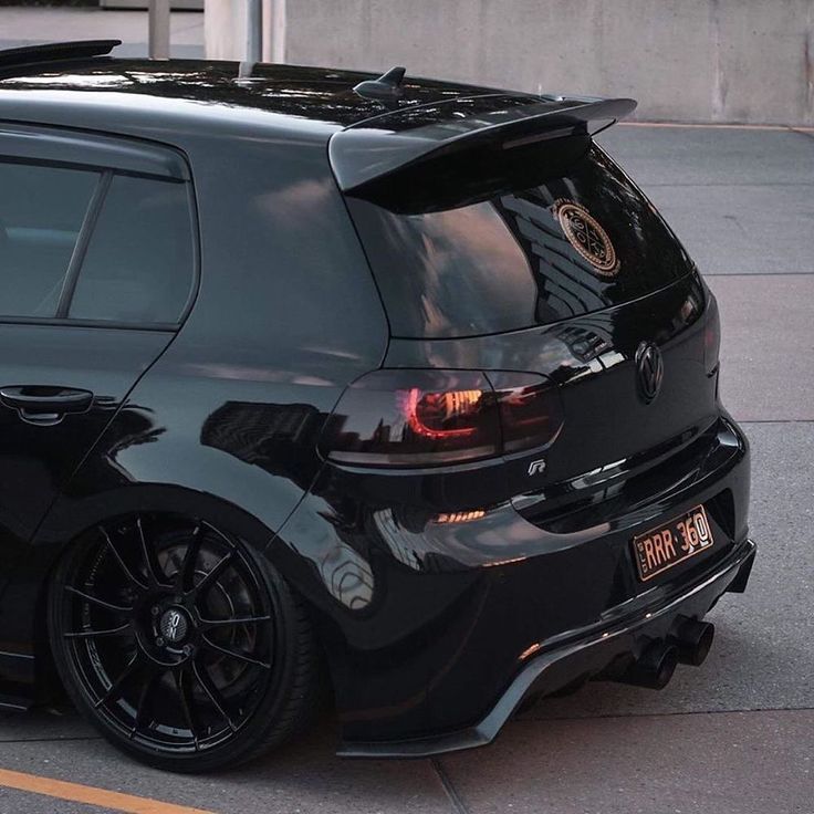 the back end of a black car parked in a parking lot