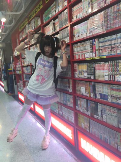 a girl standing in front of a book shelf