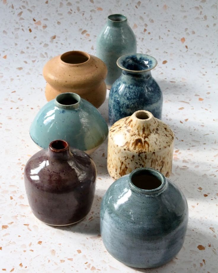 several different colored vases sitting on a white surface