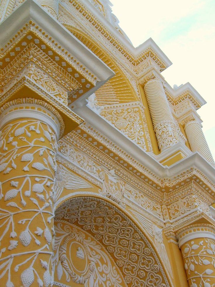 an ornate yellow and white building with arches