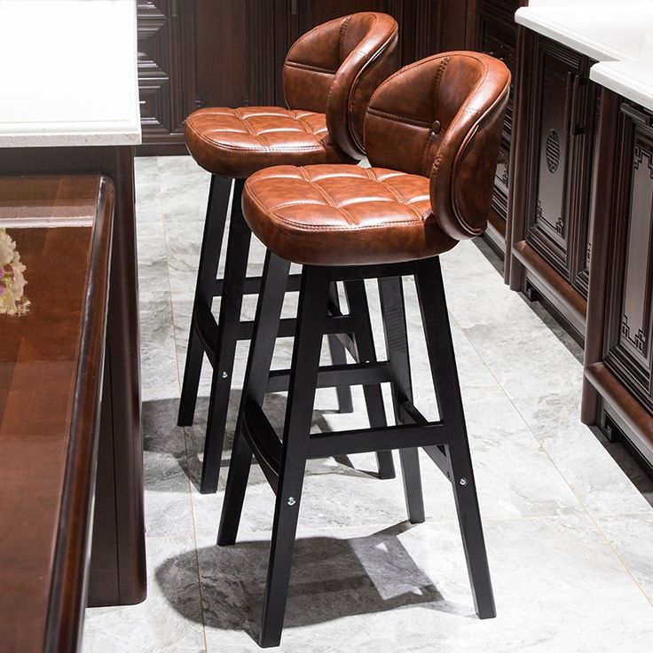 three brown leather bar stools sitting in front of a kitchen island with marble counter tops