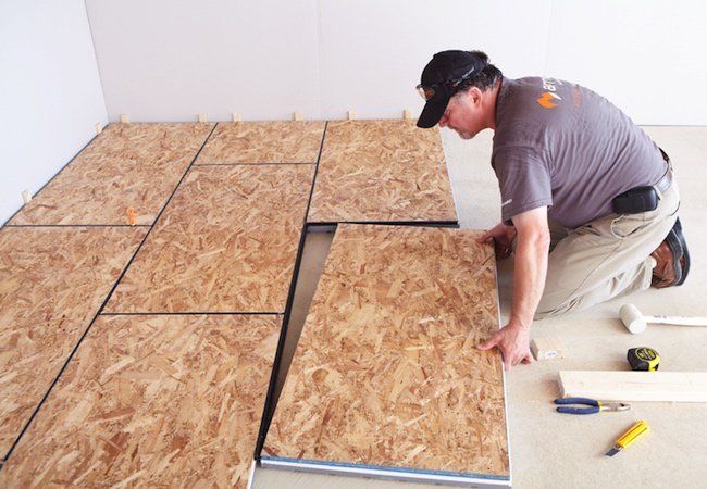 a man laying down plywood on the floor