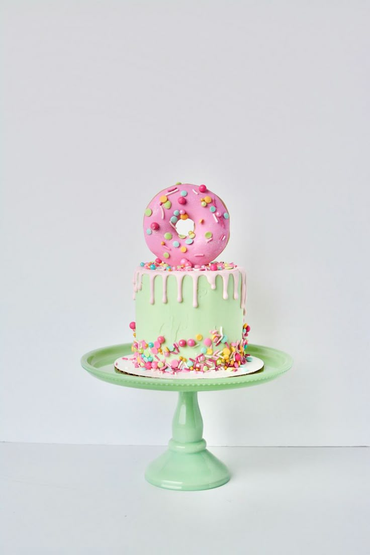 a green cake with pink frosting and sprinkles on it sitting on a plate