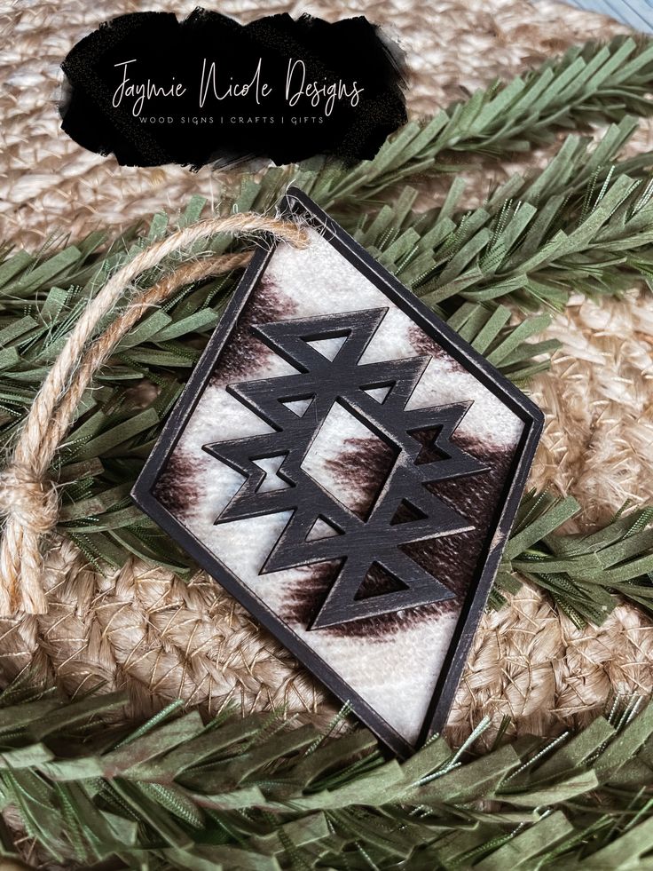 an ornament hanging from a rope on top of a rug with pine needles