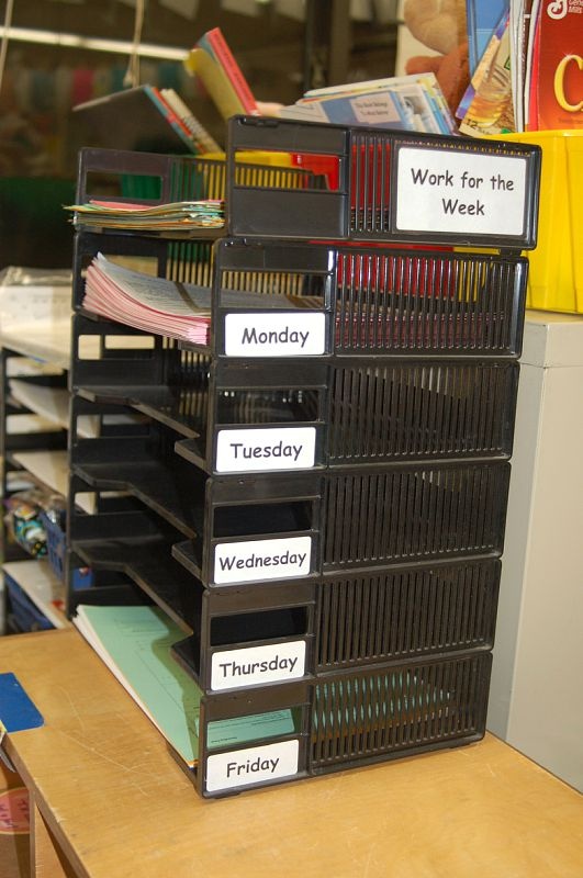 a stack of file folders sitting on top of a wooden desk next to a pile of books