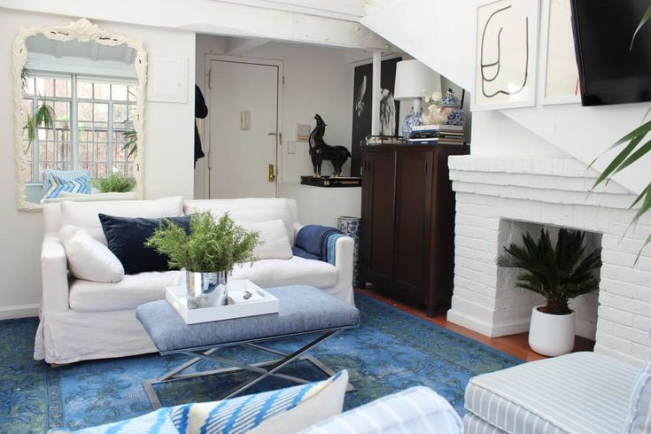 a living room filled with furniture and a fire place under a staircase leading up to a second floor