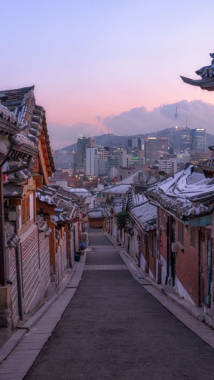 an alley leading to the city with tall buildings in the background at sunset or dawn