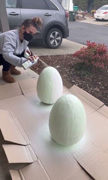 a woman is painting two large balls on the side of a cardboard box with glue