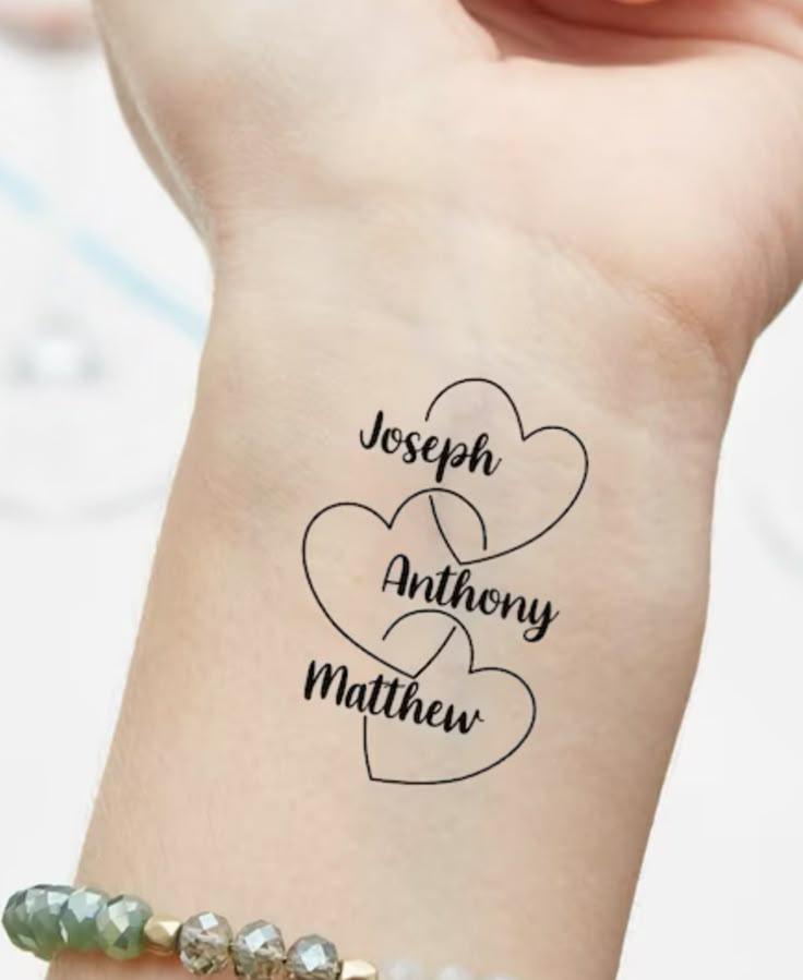 a woman's wrist with two hearts and the words joseph anthony mathieu on it