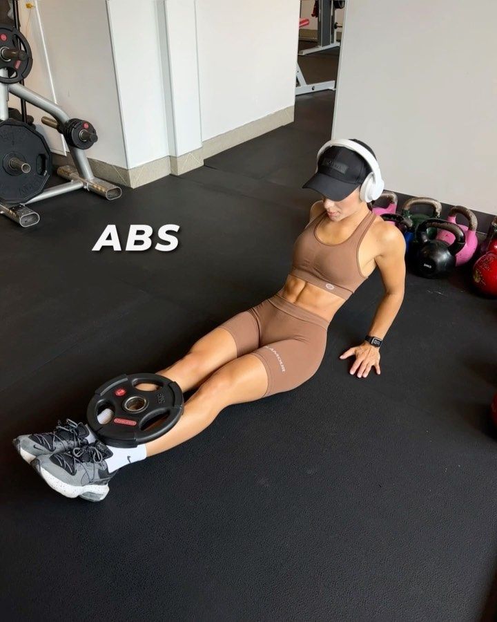 a woman laying on the ground with headphones in her ears and wearing a sports bra