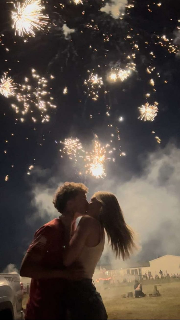 a man and woman kissing in front of fireworks