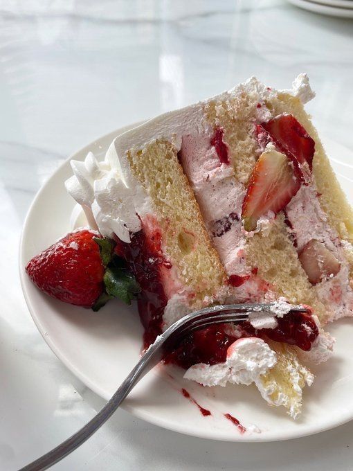 a piece of cake with strawberries on it and a fork in the foreground