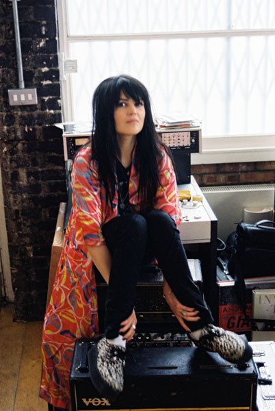 a woman sitting on top of a black suitcase