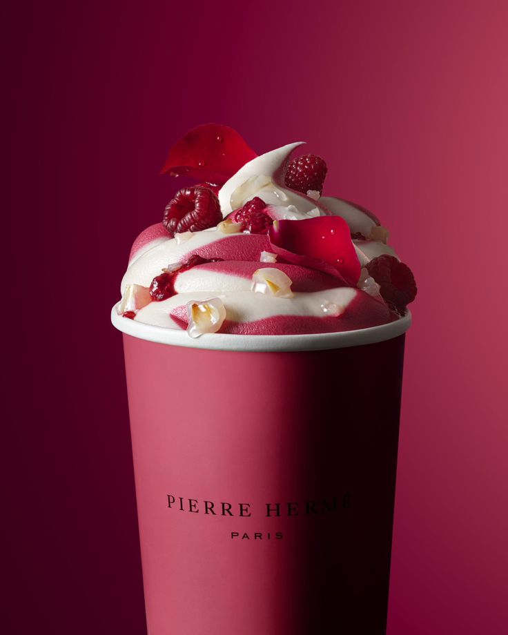 a pink cup with white frosting and raspberries on the top is shown