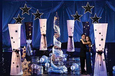 a man and woman standing in front of a stage with stars on the curtained walls