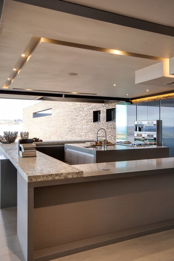 a modern kitchen with an island countertop and stainless steel appliances, along with glass doors to the outside