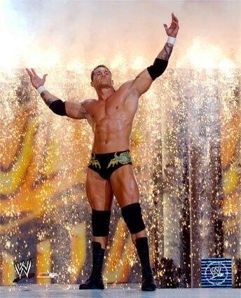 a man with his arms in the air while standing on top of a wrestling ring