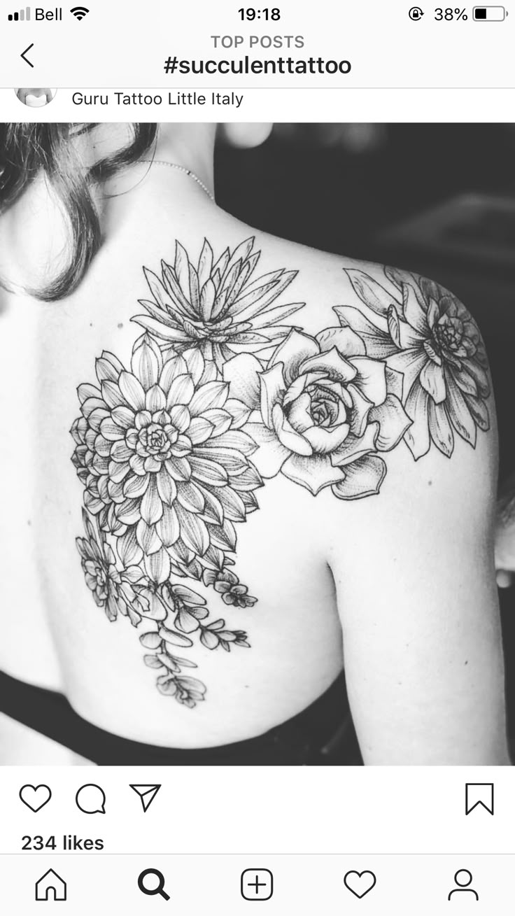 the back of a woman's shoulder with flowers and leaves tattooed on her chest