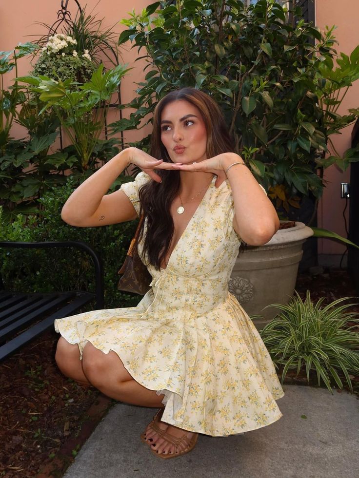 a woman in a yellow dress is sitting on a bench and posing for the camera