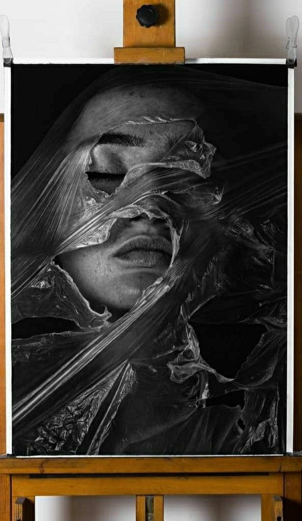 a black and white photo of a woman's face wrapped in plastic on an easel